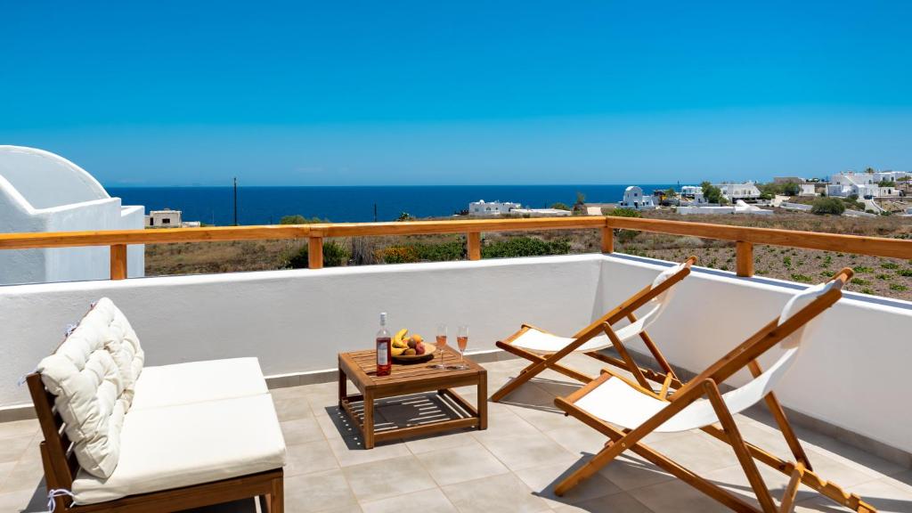 a balcony with two chairs and a table and the ocean at Johnny’s House in Imerovigli