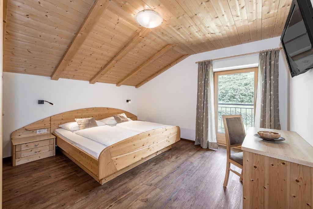 een slaapkamer met een bed, een bureau en een televisie bij Appartements Toni in Feldthurns