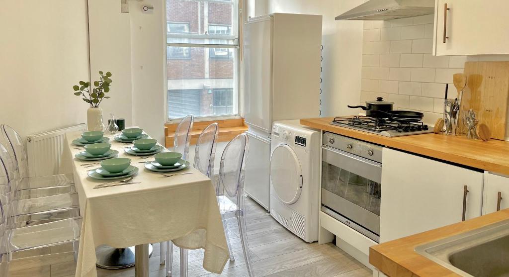 uma cozinha com uma mesa com pratos verdes em Archway Station Big Bedroom Flat em Londres