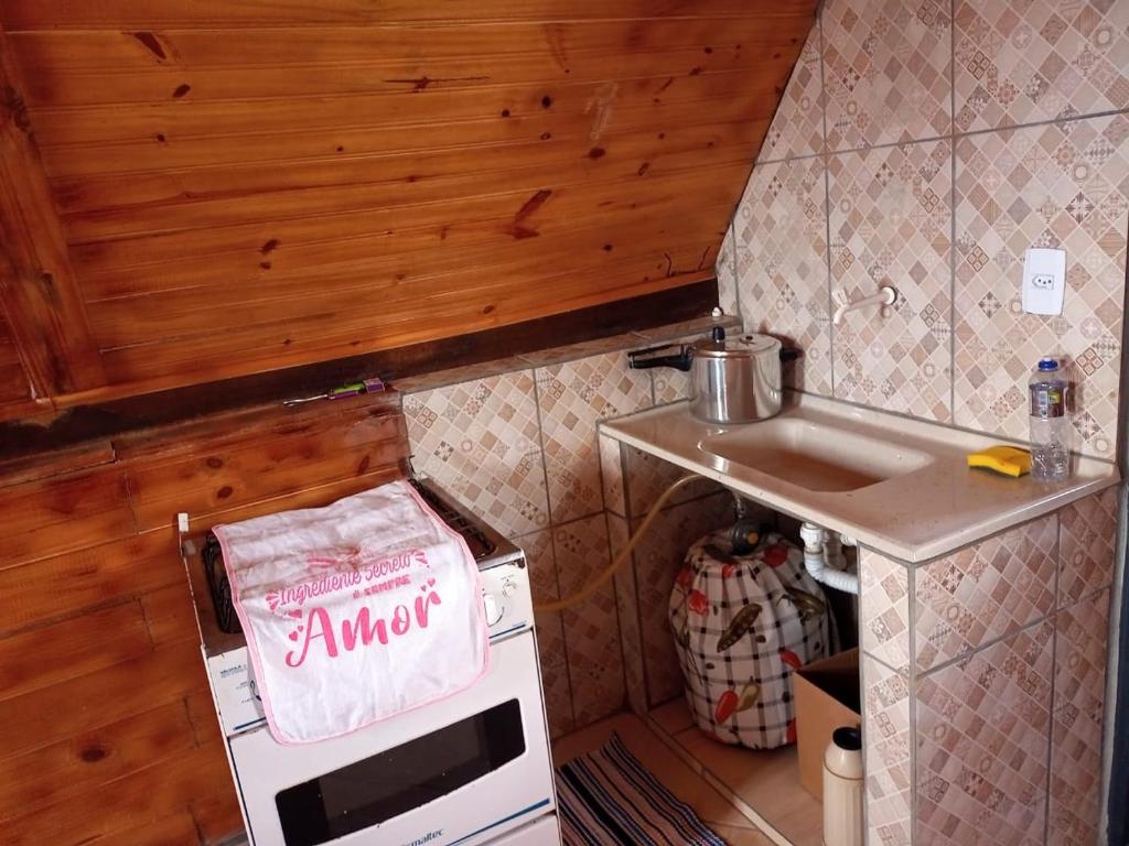 una pequeña cocina con fregadero y microondas en Chalé Nascer do Sol, en São Thomé das Letras