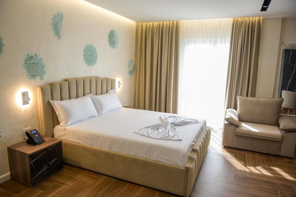 a bedroom with a bed and a chair and a window at Hotel Royal in Shkodër