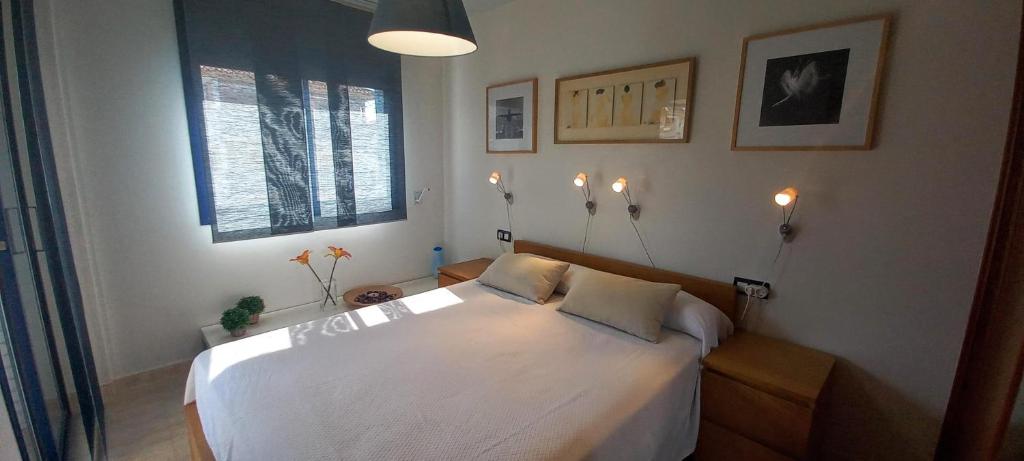 - une chambre avec un lit blanc et des lumières sur le mur dans l'établissement BLAU MARÍ 175, à Calafell