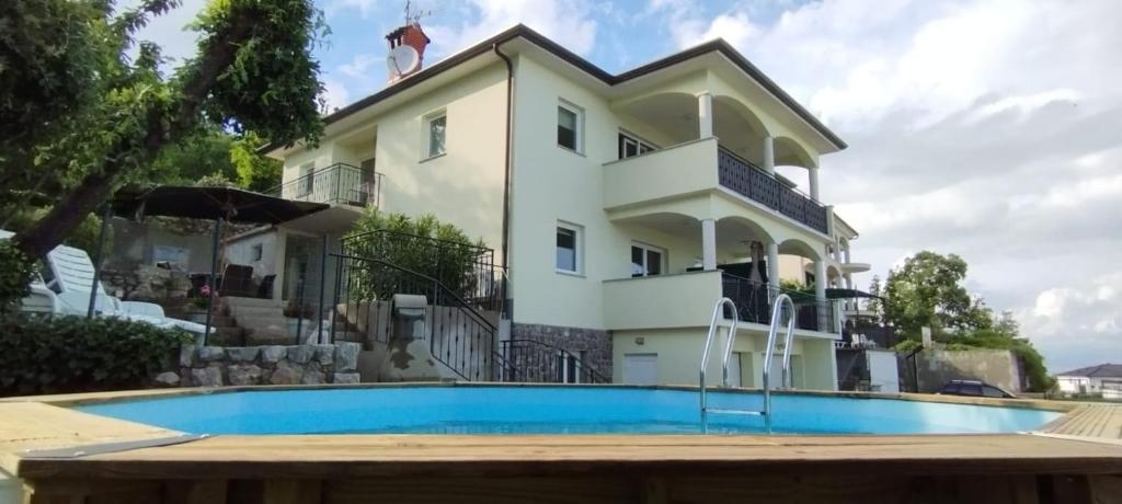 een huis met een zwembad ervoor bij Apartment Kyra in Lovran