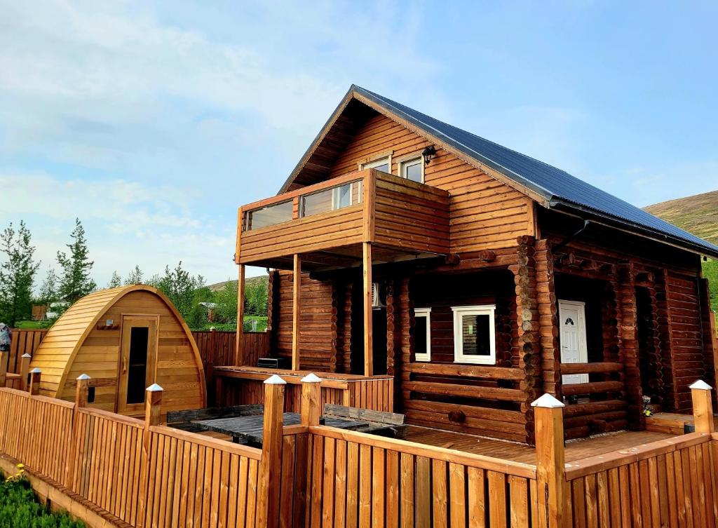 a large wooden cabin with a wooden fence at Akureyri Loghouse in Akureyri
