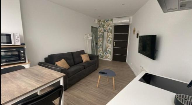 a living room with a black couch and a kitchen at Studio à 2 pas de la plage in Marseille