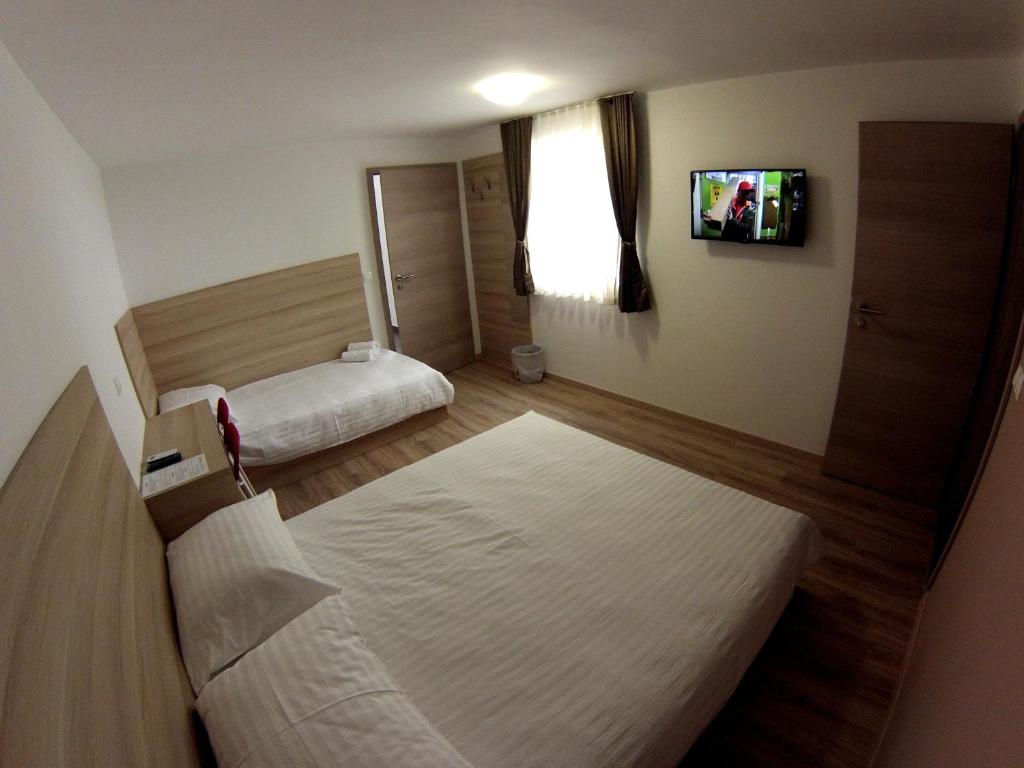 a hotel room with two beds and a tv at Sweet Dreams Rooms and Apartments Postojna in Postojna