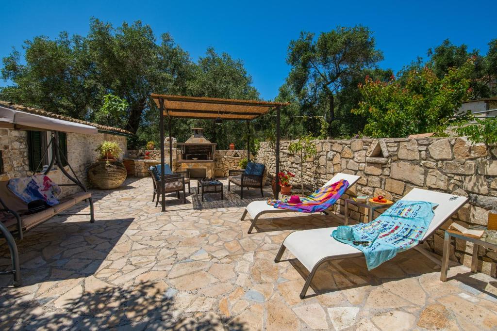 a patio with chairs and a stone wall at Ionian Stone Home with Terrace in Bogdanátika