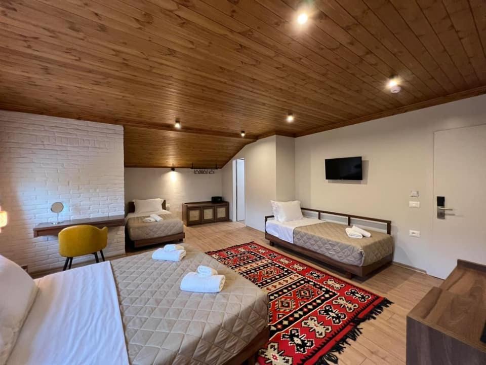 Habitación grande con 2 camas y TV. en The Stone Sky Hotel, en Gjirokastra