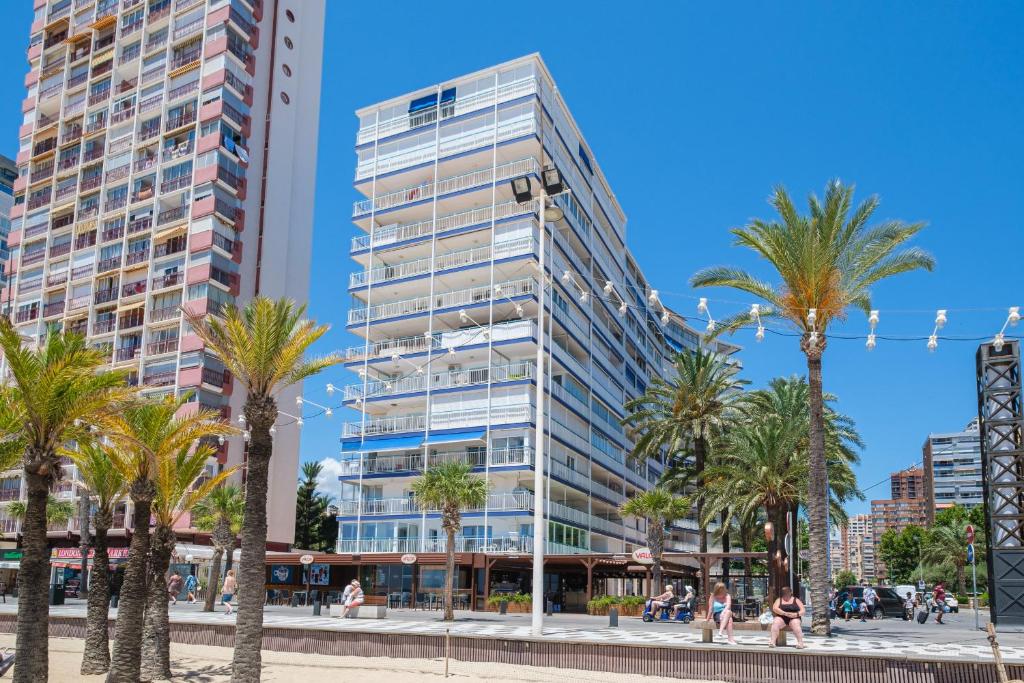 un grand bâtiment avec des palmiers devant lui dans l'établissement Copacabana Apartment 4-C Levante Beach, à Benidorm