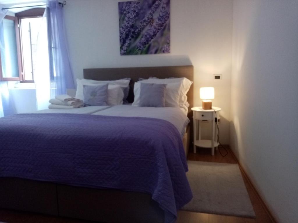 a bedroom with a bed with a blue comforter and a window at Rooms Serafin-Lavanda in Motovun