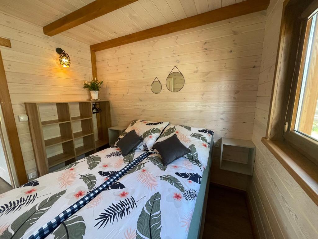 a bed in a room with a wooden wall at Leśne Dziady Borsk in Borsk