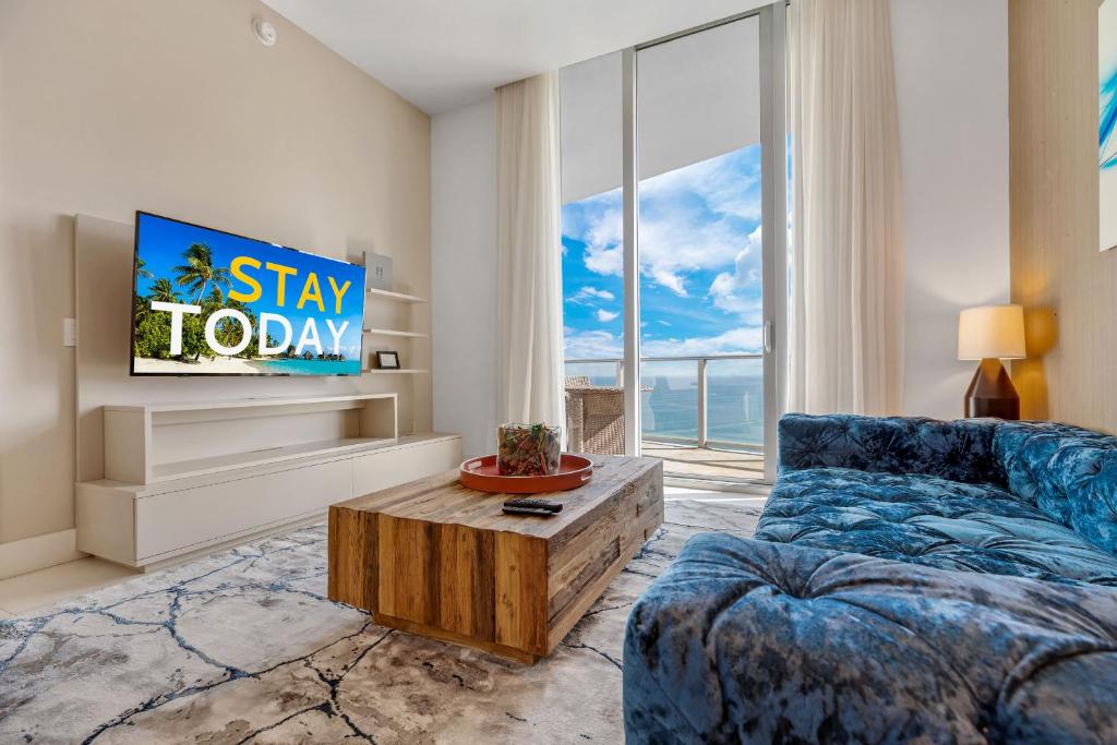 a living room with a blue couch and a tv at Picturesque Beachfront Condo #4105 - LOVELY 2BD and 2BA PENTHOUSE WITH DIRECT OCEAN VIEW in Hollywood