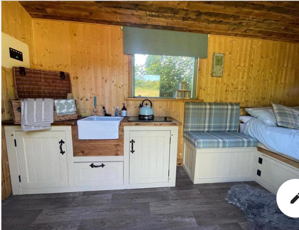 una cocina con fregadero y una cama en una habitación en Cosycoopmiskineggs, en Llantrisant