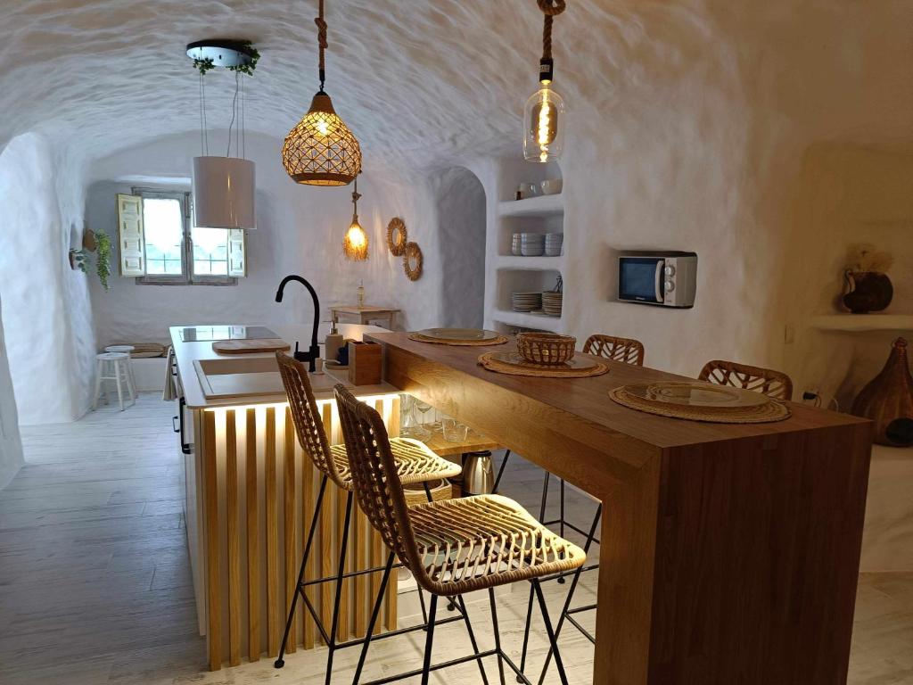 uma cozinha com uma grande ilha com cadeiras e uma mesa em Cueva OTTO Familiar Privada em Baza