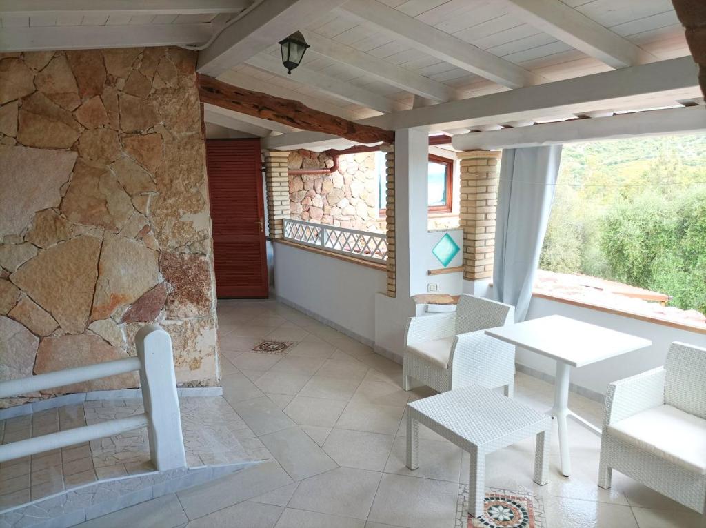 a room with a table and chairs and a stone wall at Sardinia Yellow House in Solanas