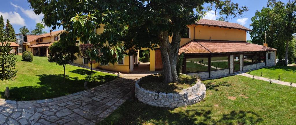 una casa con un árbol en medio de un patio en Agriturismo Roseto, en Serra San Bruno