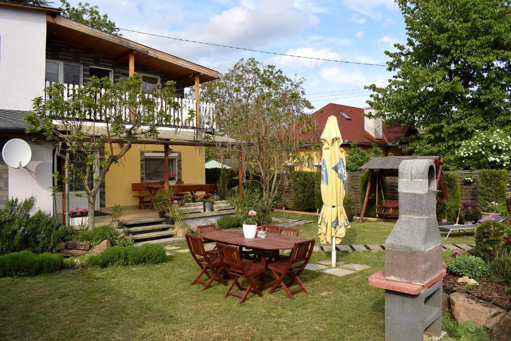 un jardín con una mesa y una sombrilla y una casa en Liliom Apartman, en Balatonvilágos