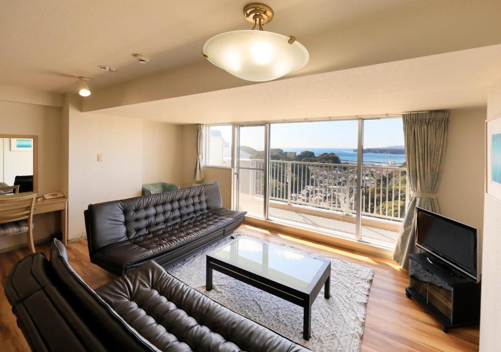 ein Wohnzimmer mit einem Ledersofa und einem großen Fenster in der Unterkunft Katsuura Hilltop Hotel & Residence - Vacation STAY 73528v in Katsuura