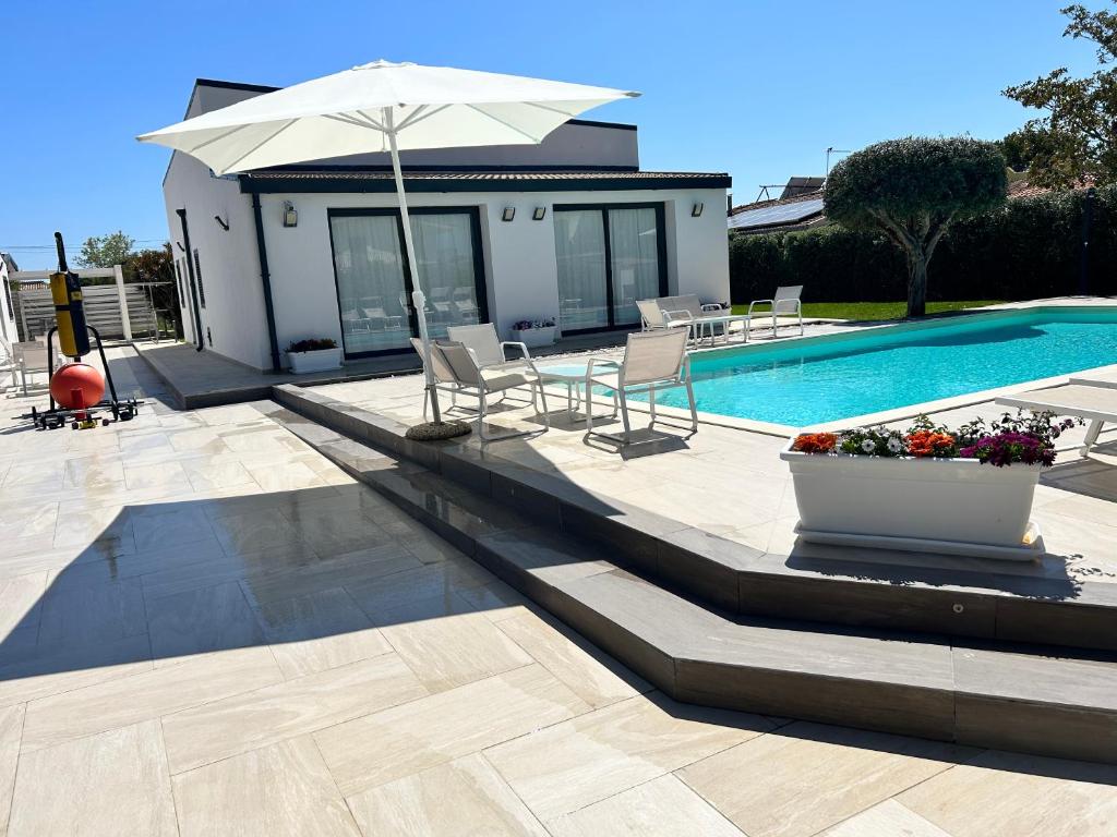 una casa y una piscina con sombrilla y sillas en Villas Sport And Beach en Fanusa