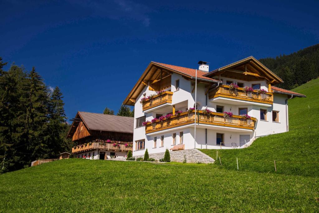 un grand bâtiment blanc au sommet d'une colline verdoyante dans l'établissement Perchnerhof, à Terento