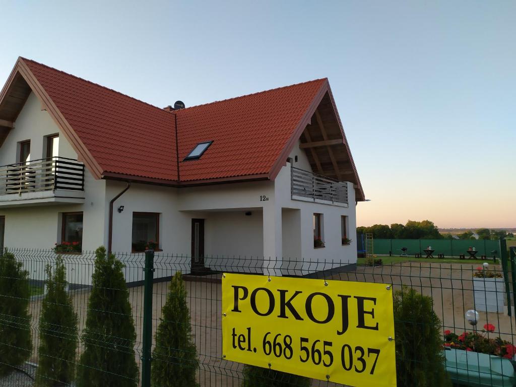 una casa con un cartel de venta delante de ella en Pokoje u Krysiaków en Mikołajki