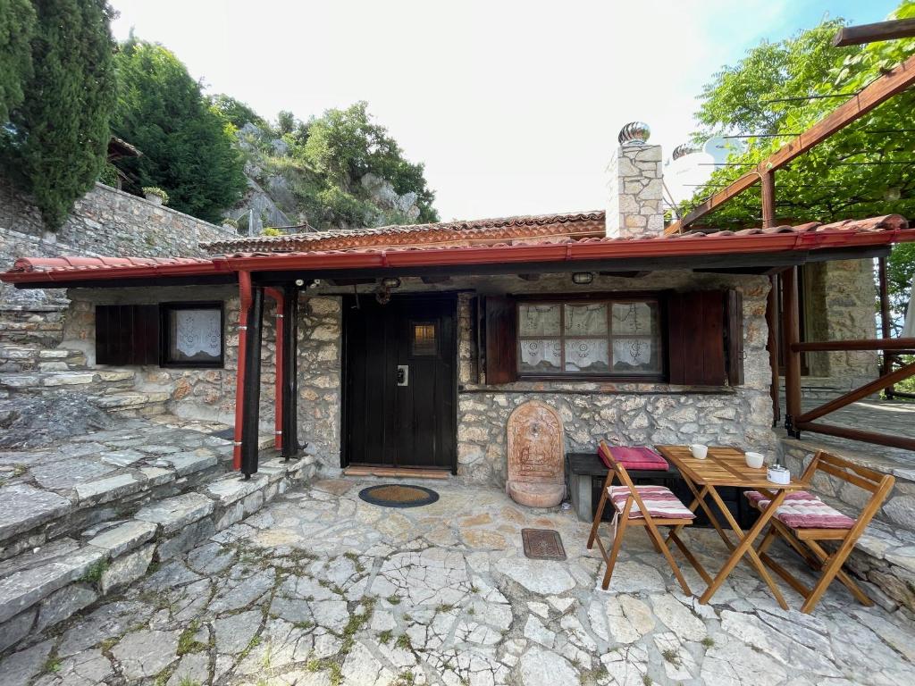 una casa de piedra con una mesa y sillas delante de ella en Agoriani Art Studio - Sweet little cottage en Lílaia