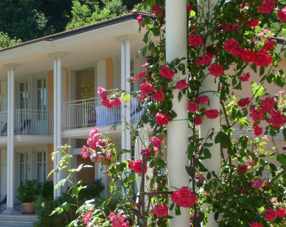 a white house with pink flowers in front of it at Ville Lago Lugano in Porto Ceresio