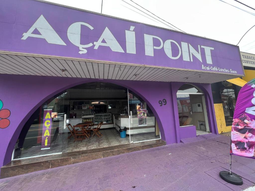 een paarse winkel met een tafel en stoelen erin bij Açaipoint Hostel in Águas da Prata