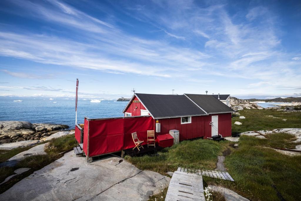 czerwony dom na brzegu oceanu w obiekcie Jomsborg Ilulissat w mieście Ilulissat