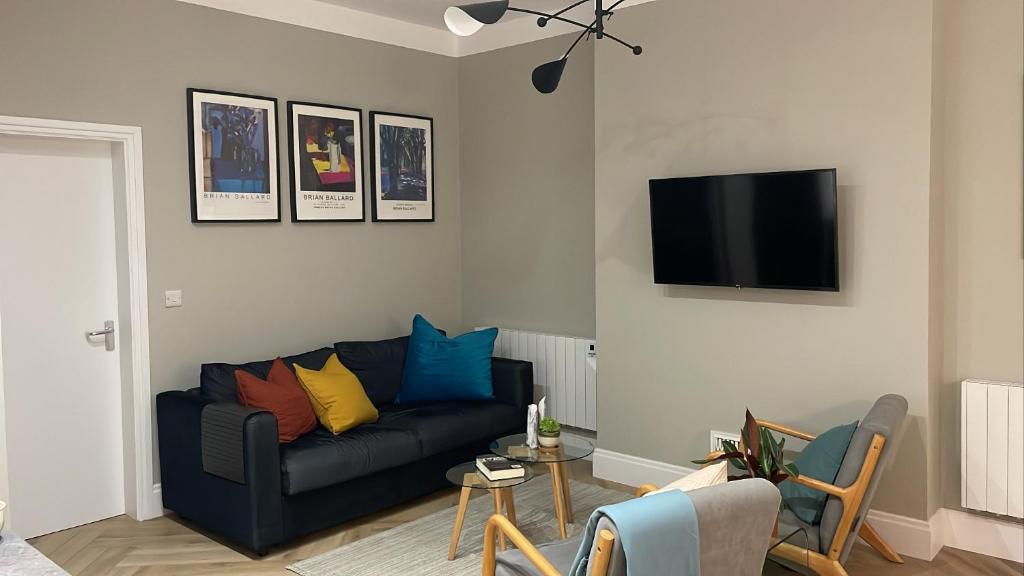 ein Wohnzimmer mit einem Sofa und einem TV an der Wand in der Unterkunft CityGo Apartments Queens in Belfast