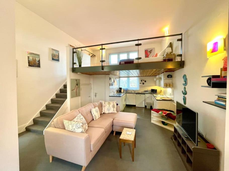 a living room with a couch and a staircase at High-Ceiling Flat with Rooftop & Skyline View in London