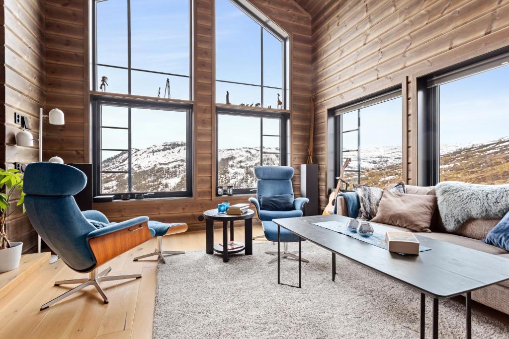 a living room with a couch and chairs and windows at Rindabakkane Lodge in Sogndal