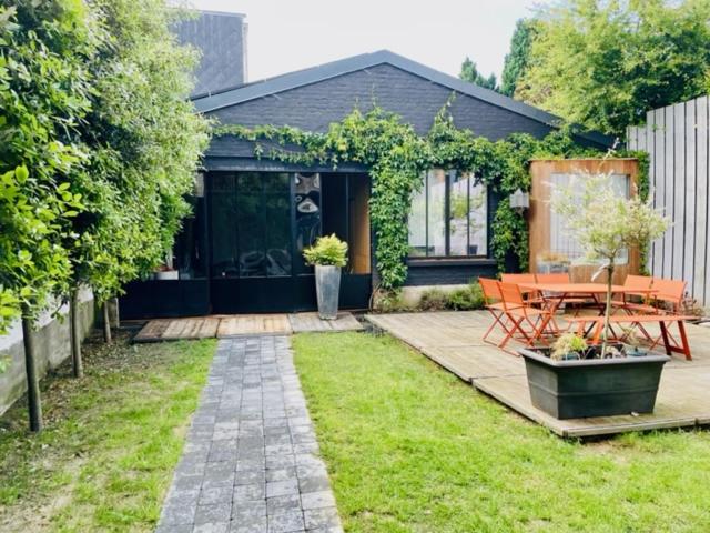 a house with a patio with a table in the yard at Hangar 336 in Menen