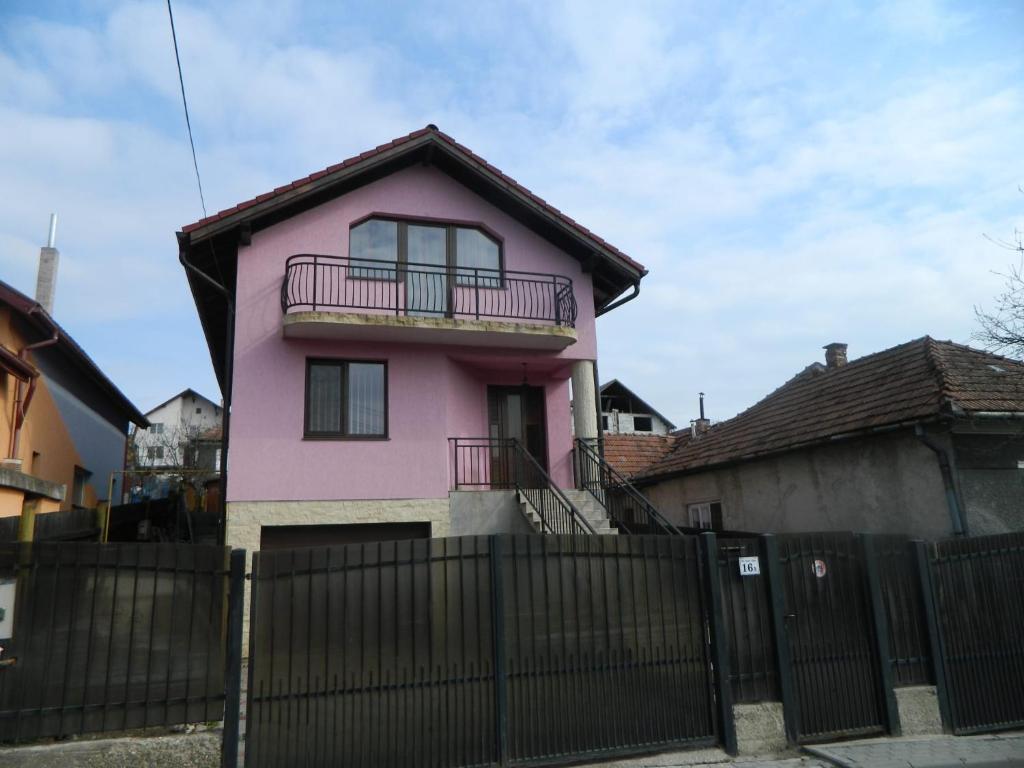 una casa rosa con una valla delante en Villa Blacky en Cluj-Napoca