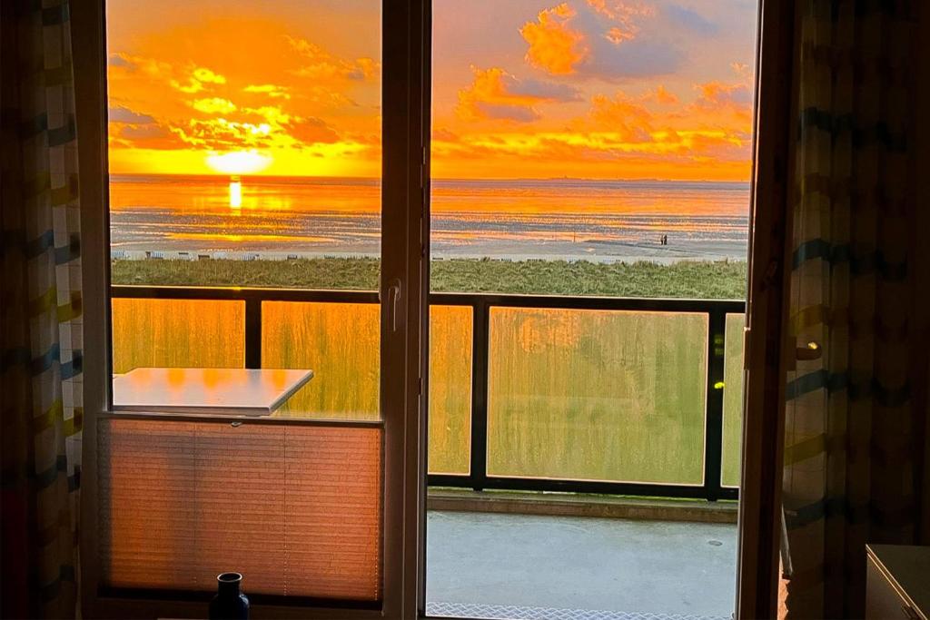 a window with a view of the beach and the sunset at Beach Lodge BL04 in Cuxhaven