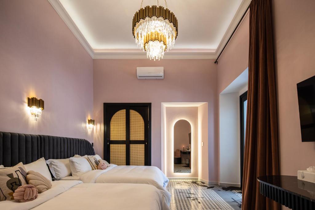 um quarto com 2 camas e um lustre em HOLT Hotel De Mi Independencia Double Queen Room em Oaxaca de Juárez