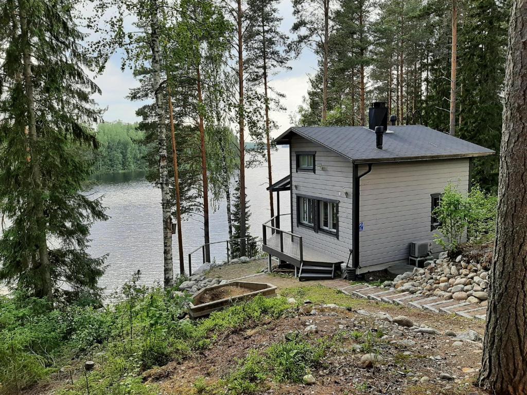 ein kleines Haus im Wald neben einem Wasserkörper in der Unterkunft Villa Ulappa in Savonlinna