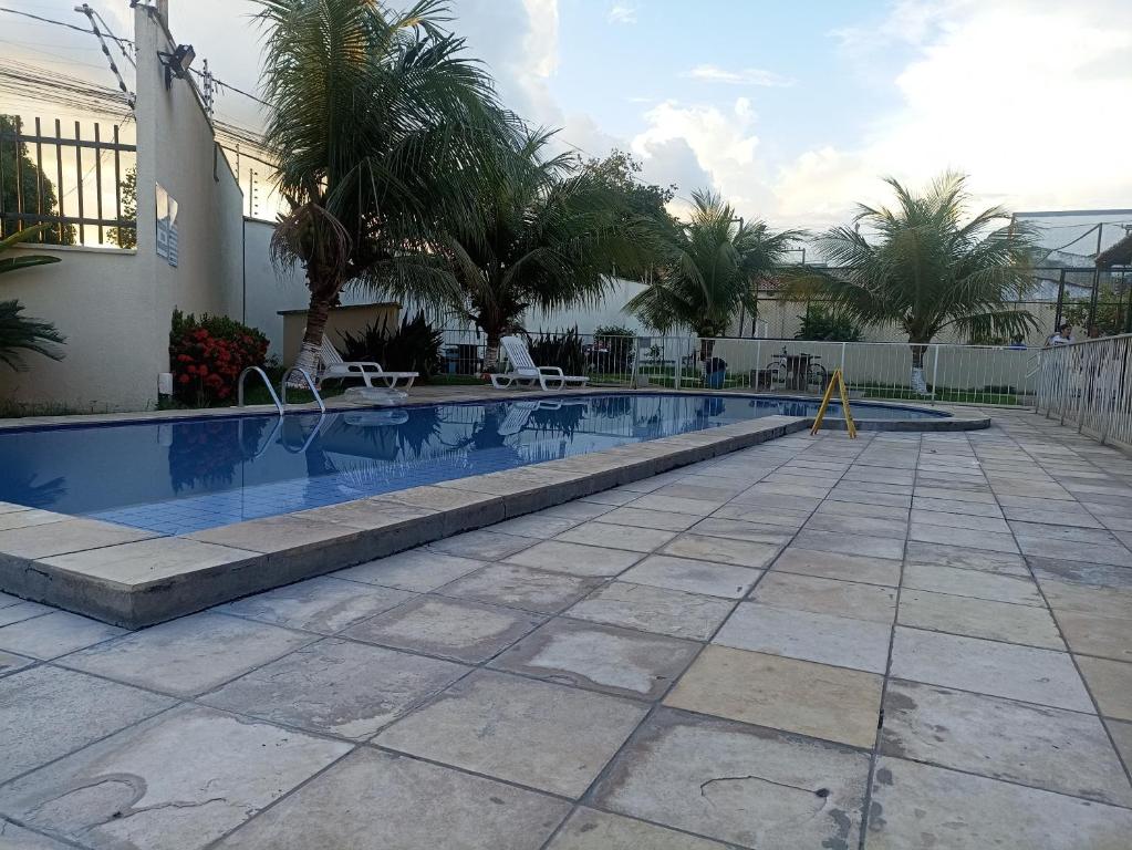 a swimming pool with palm trees next to a building at Apto em condomínio , portaria 24h, com área de lazer, ideal para famílias in Imperatriz