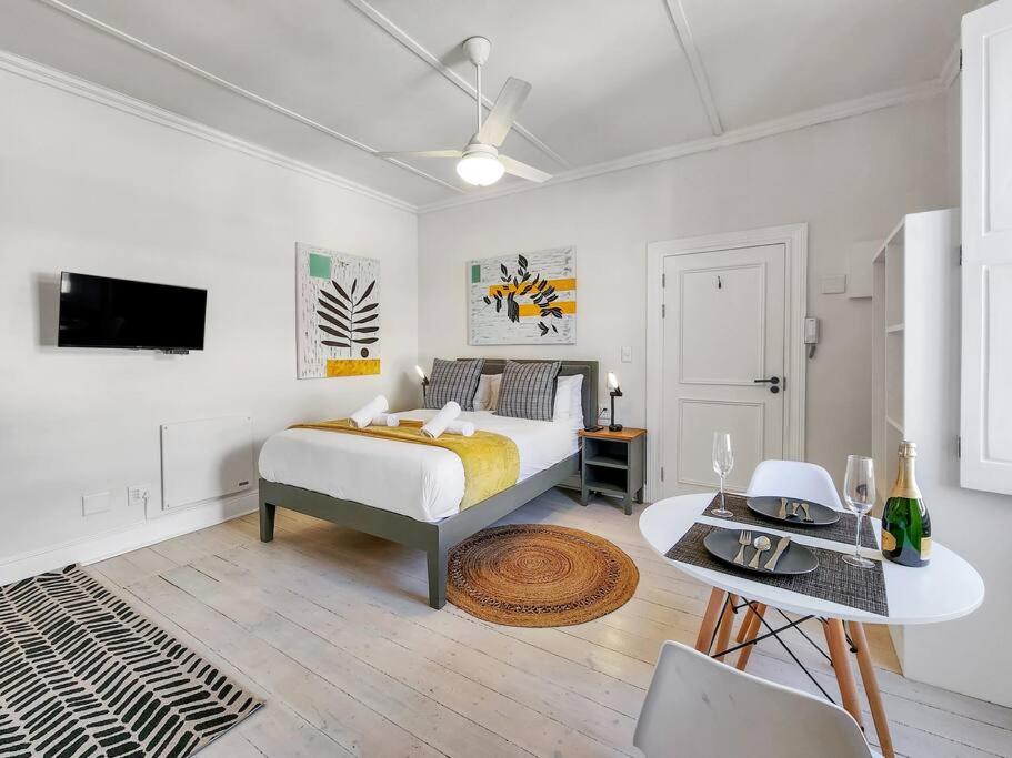 Dormitorio blanco con cama y mesa en Classy and Newly Renovated Studio in Observatory, en Ciudad del Cabo