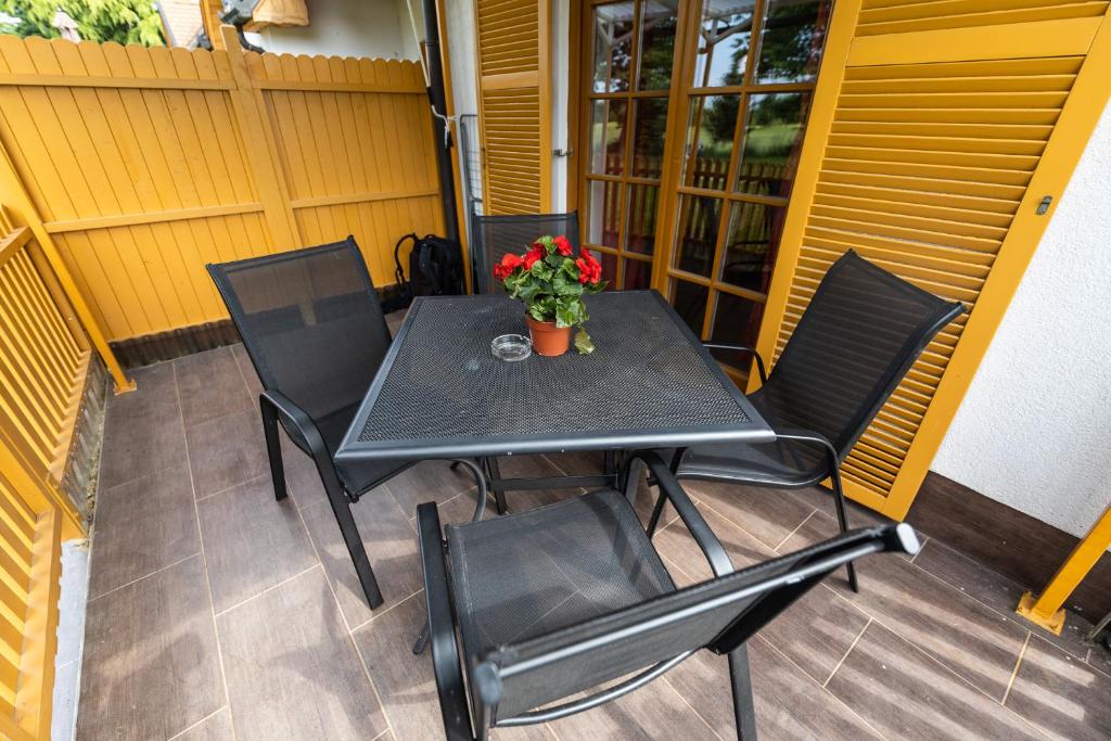 Apartma Trobentica 15 in 3 Moravske Toplice في مورفسكه تيبليتسه: طاولة سوداء وكراسي على شرفة مع الزهور