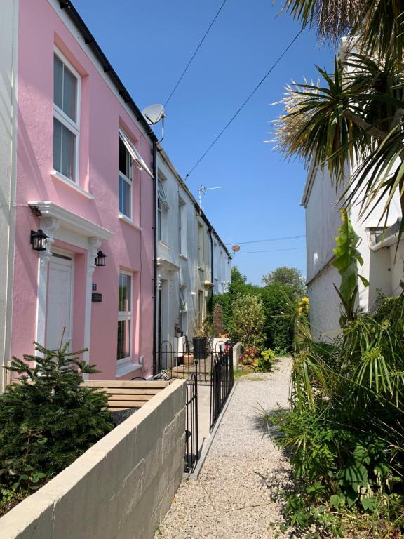 a pink house with a fence next to a sidewalk at The Pink House in Falmouth