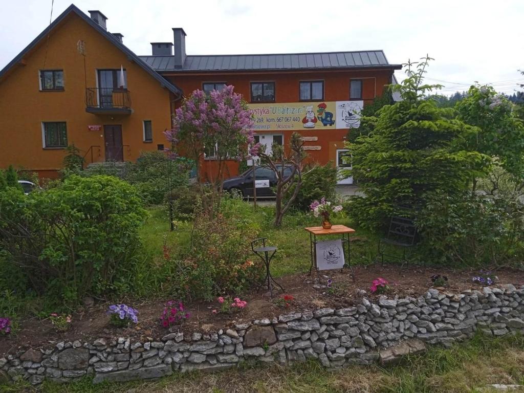 un jardín frente a una casa con una pared de piedra en Agroturystyka U Baltazara, en Duszniki-Zdrój