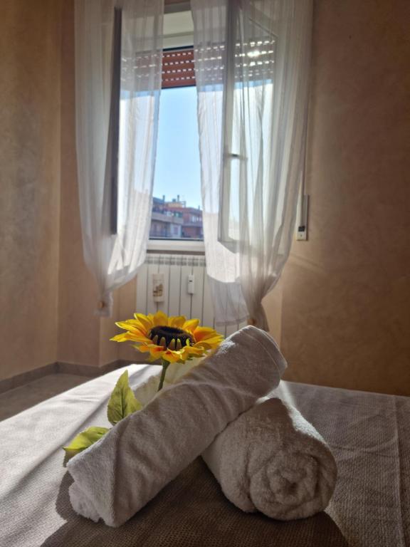 a bouquet of flowers on a bed with a window at Posto al sole in Lido di Ostia