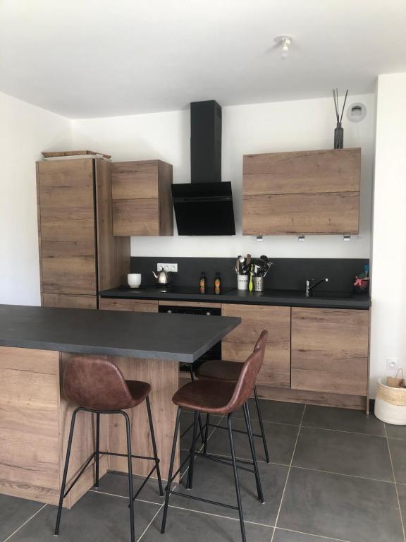 une cuisine avec un comptoir noir et des armoires en bois dans l'établissement Appartement Aix en Provence vue Ste Victoire - BATIMENT B11 - 13090 AIX EN PROVENCE, à Aix-en-Provence