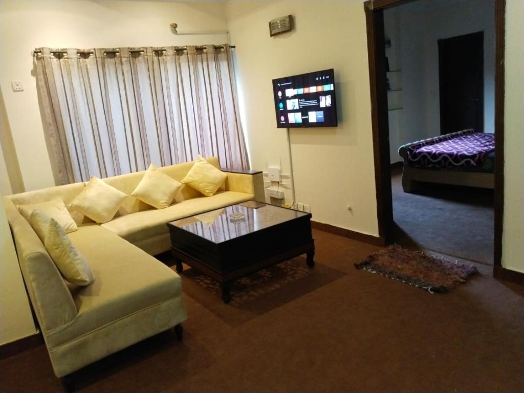a living room with a couch and a table and a mirror at Luxury 2BR Family Apt/Wi-Fi / Netflix in Islamabad