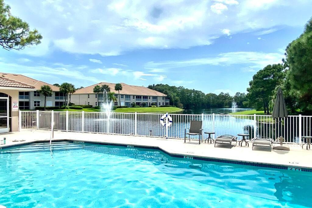 a pool with chairs and a fence and a fountain at Luxury condo near Wiggins pass beach & park in Naples