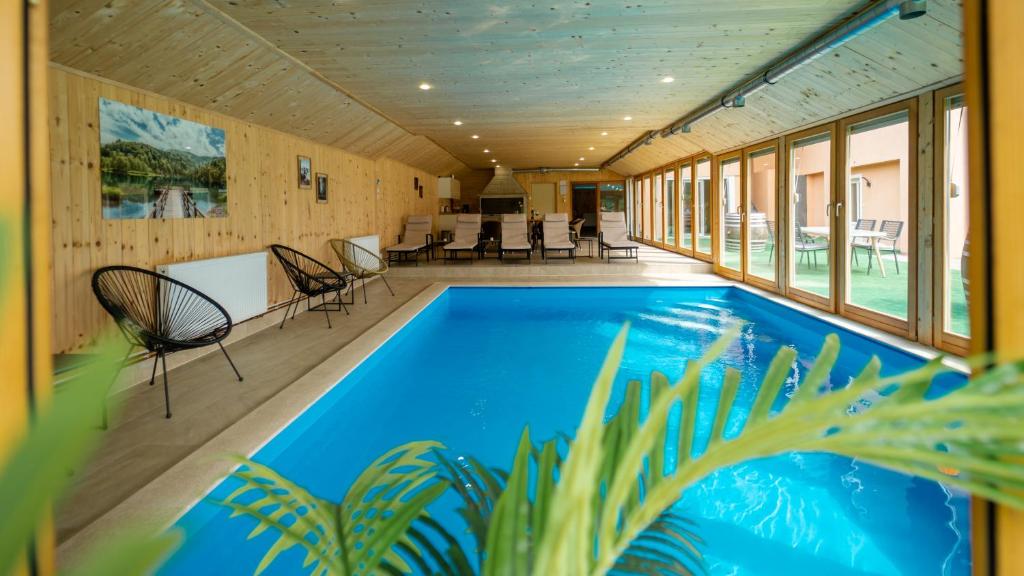 a swimming pool in a house with windows at Apartman DAVID sa unutarnjim bazenom in Brod Moravice