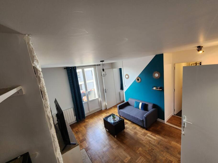 a living room with a couch and a blue wall at L&#39;Escale Lafayette - Appartement Rive Gauche in Rouen