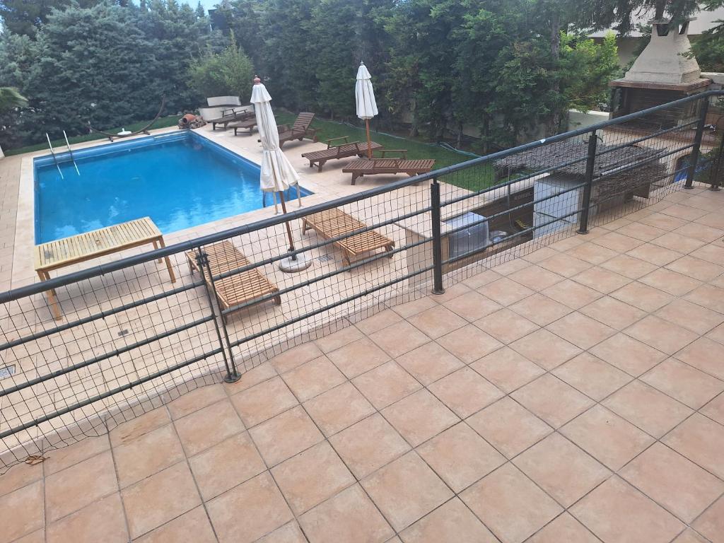 a fence around a swimming pool with chairs and umbrellas at Kantza Private Pool Project, near metro, A 60sm lux pool for your use only in Leondárion