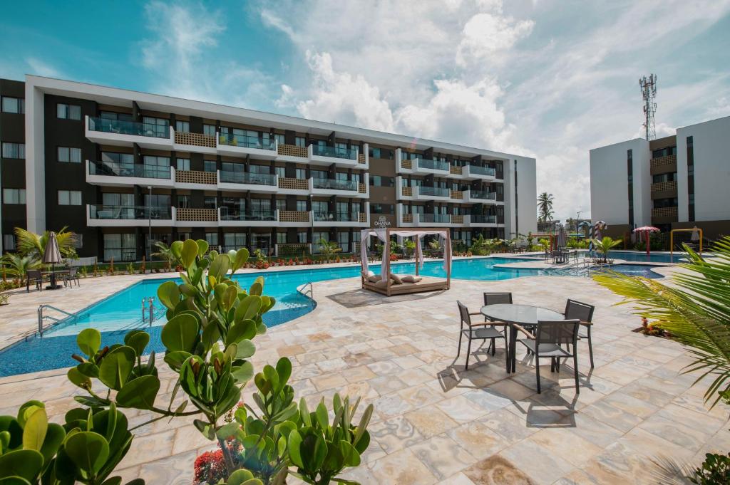 una piscina con tavolo e sedie di fronte a un edificio di MANA BEACH EXPERIENCE by AFT Porto de Galinhas, Muro Alto a Porto De Galinhas